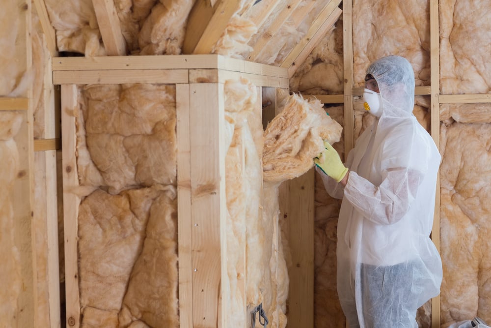 Worker filling walls with insulation material in construction site-1